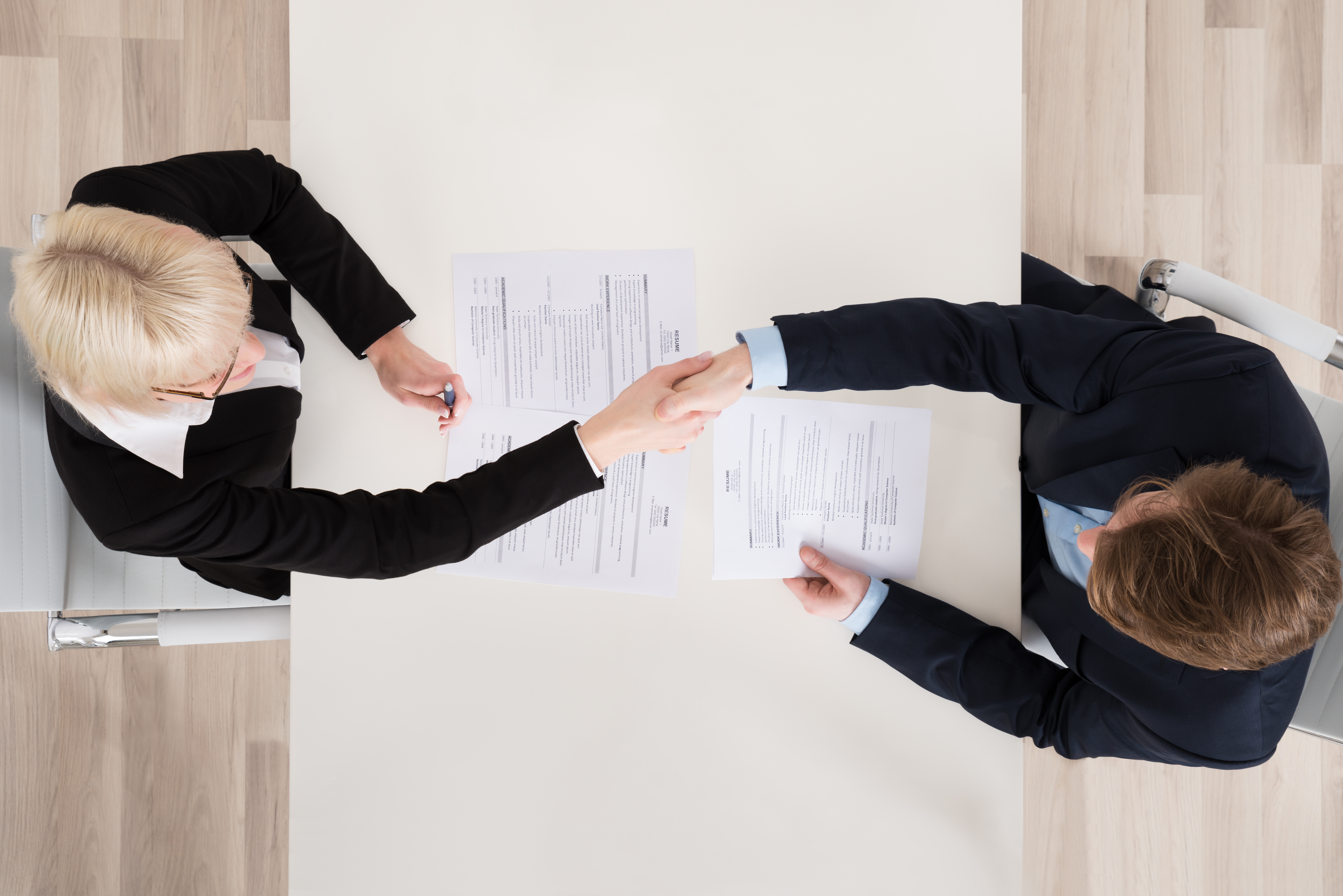 High Angle View Of Two Businesspeople Shaking Hand In Office